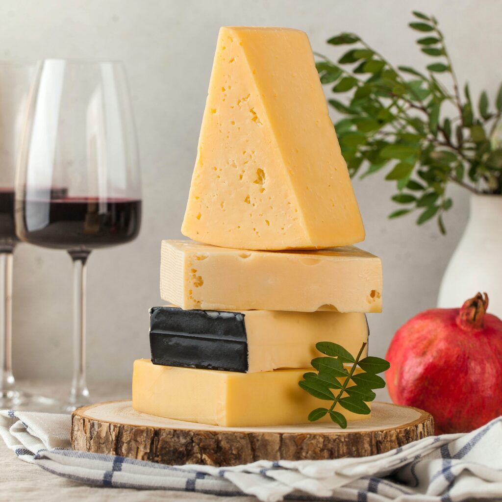 Assorted cheeses on a wooden board and a linen tablecloth.