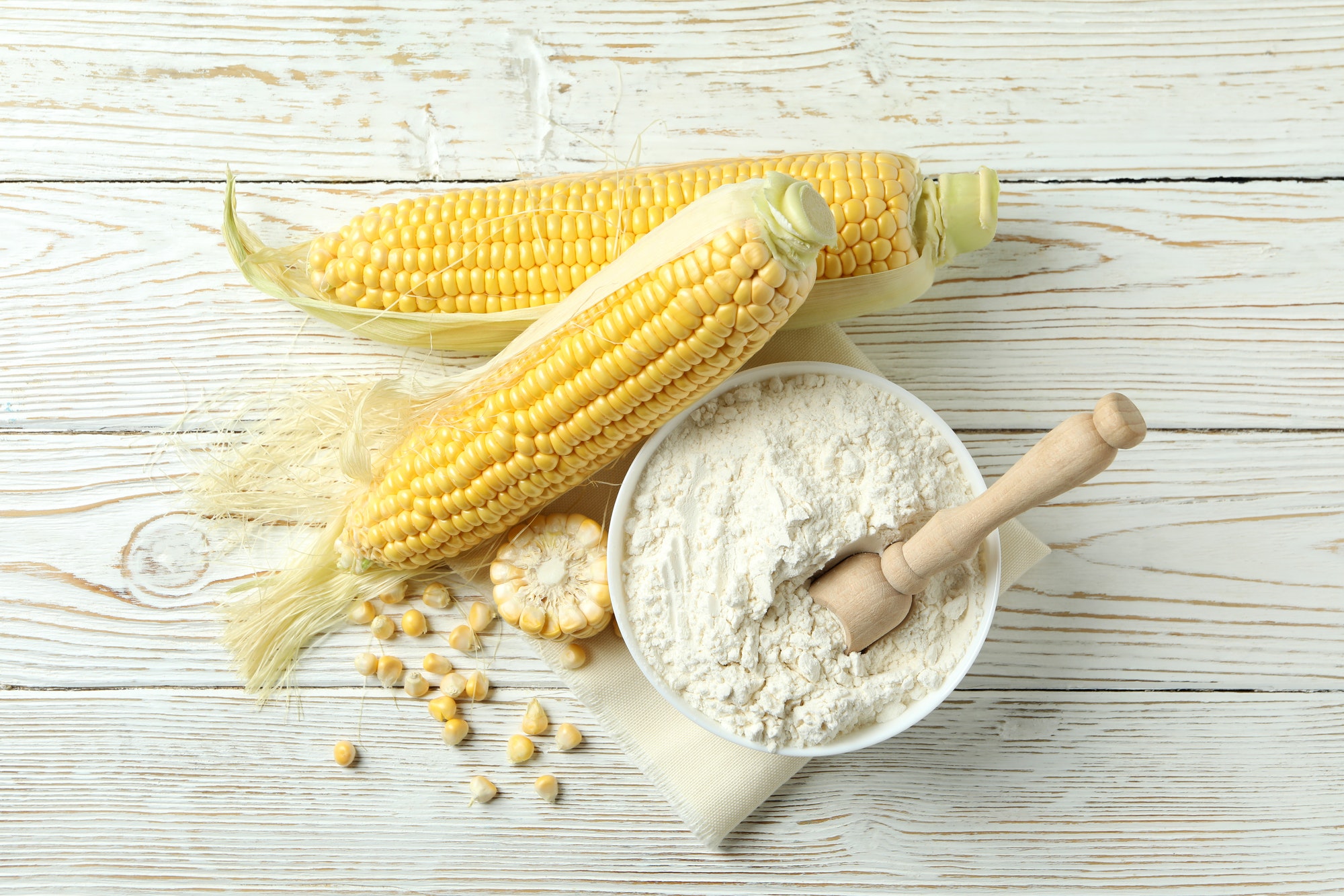 Raw corn and flour on white wooden table Raw corn and flour on white wooden table